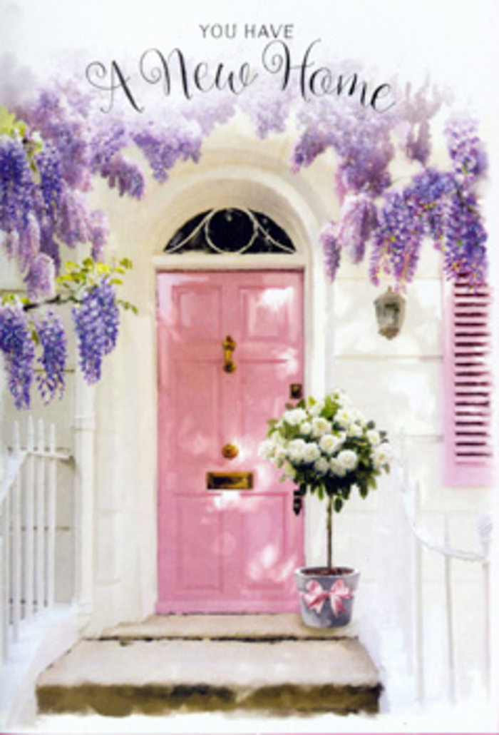 The scene shows a doorway that could easily belong to a converted warehouse flat in Shoreditch, softened and romanticised through careful floral styling. The front door, painted in a soothing shade of pink somewhere between blush and rose, is set within a whitewashed wall whose surface bears slight, irregular textures, catching the faint variations of natural light. Around the top and sides of the door, generous branches of wisteria drape downwards, their lavender blossoms dangling in loose, pendulous clusters. Each cluster is made up of many small, petal-like forms that deepen in colour as they recede into the shade, creating a gentle gradient from near-white lilac at the edges to richer purple closer to the vines. A single pastel shutter to the left or right of the door echoes the same soft colour palette, lending the façade a balanced, symmetrical feel that might remind a local of the prettiest corners near Boundary Street. At the base of the door, sitting slightly off-centre on the step, is a grey tin bucket used as an informal vase, its understated, utilitarian look accenting the refinement of the flowers it holds. Inside, white and cream roses are packed generously together, their velvety petals layered into rounded, full blooms that appear almost cloud-like. Interwoven amongst them are stems of fresh, green foliage in muted tones, adding contrast while keeping the overall mood calm and organic. A pale pink ribbon encircles the bucket and is tied in a simple, unfussy bow, picking up the blush of the door and the cooler tones of the wisteria. The composition feels intimate and hopeful, like a housewarming gesture for someone who has just moved into a new home near Shoreditch Park or the Artisan cafés off Old Street, with flowers welcoming them each time they climb the steps.